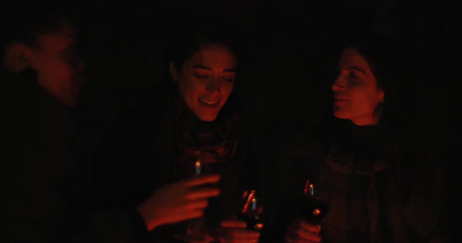 People have drinks at night by a campfire