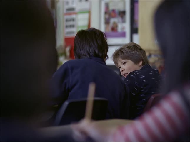 A clip of two kids conversating in class while seated