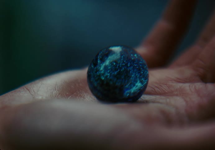 Closeup of a persons hands holding a shiny blue marble