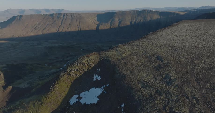 Aerial of mountains and valley containing patches of snow