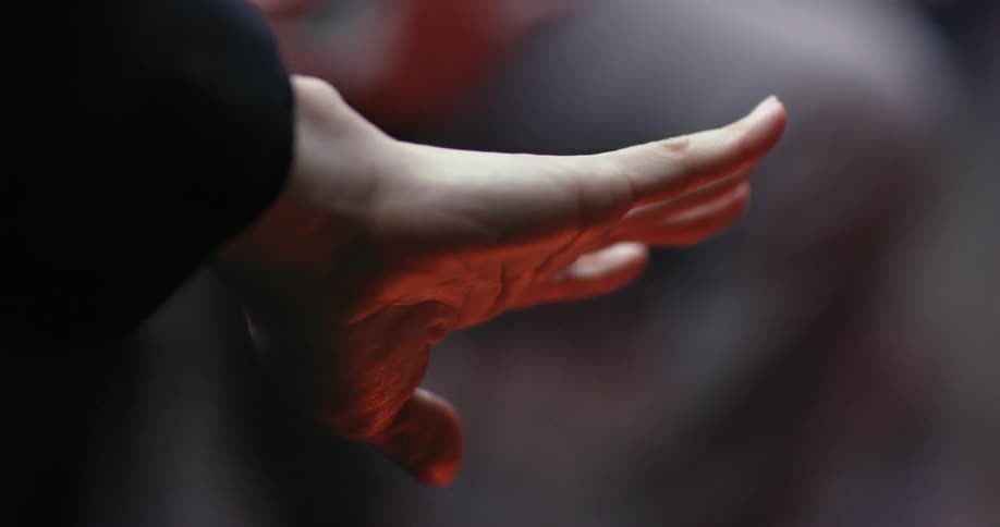 A person puts their hand out flat warming it on a fire