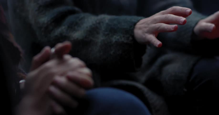 Hands warm themselves by a fire