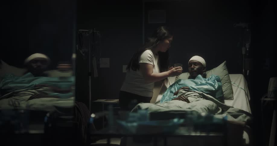 A woman gives water to a hospital patient
