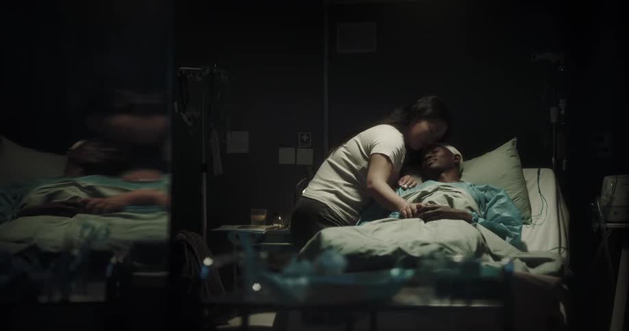 Man lying on a hospital stretcher with his wife hugging him affectionately