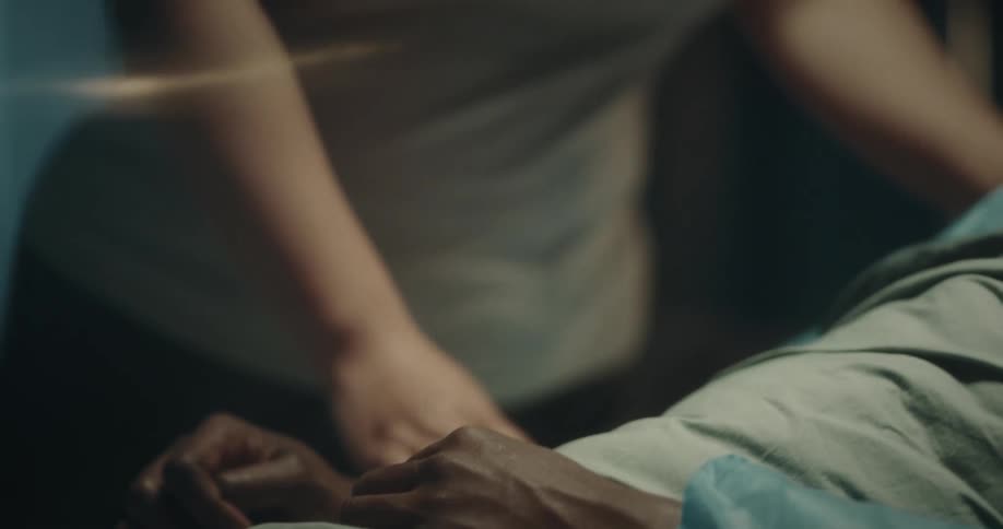 A woman approaches the hospital bed with a patient