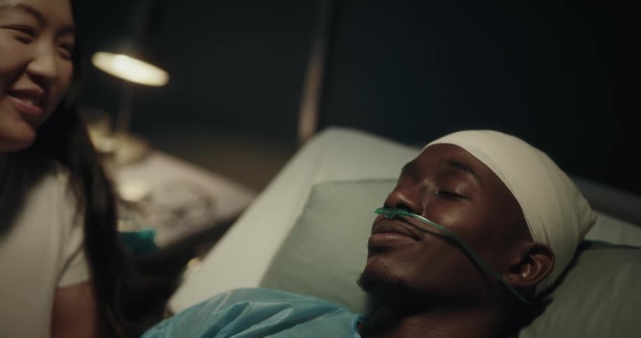 A woman caressing and giving a kiss on her partners forehead who is lying on a hospital stretcher