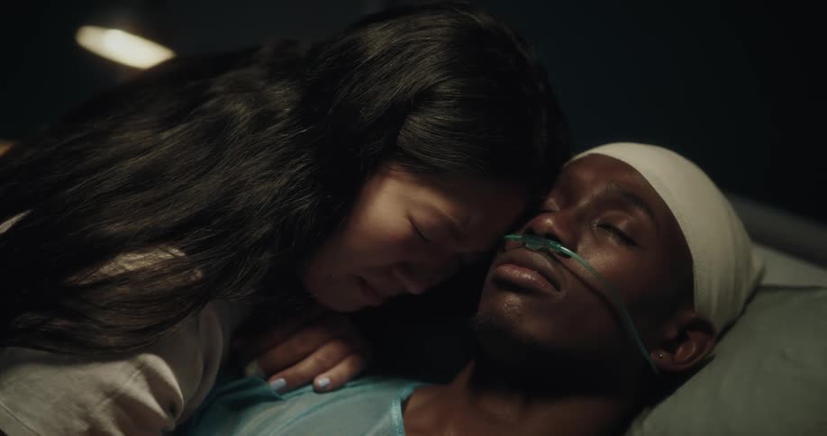 A woman caressing and crying beside her husband lying on a hospital stretcher