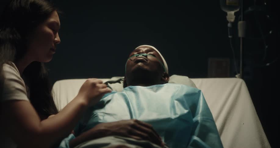 A woman caressing and giving a kiss to her partner who is on the hospital stretcher