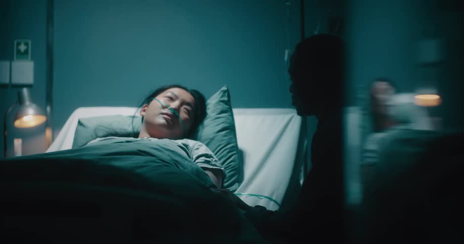 A man is talking with a woman in a hospital bed