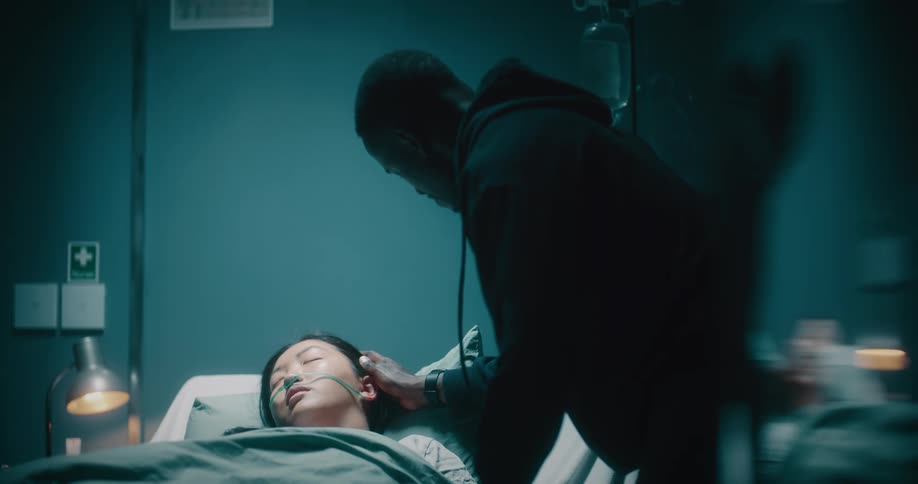 Man caressing his wifes hair as she lies on a hospital stretcher