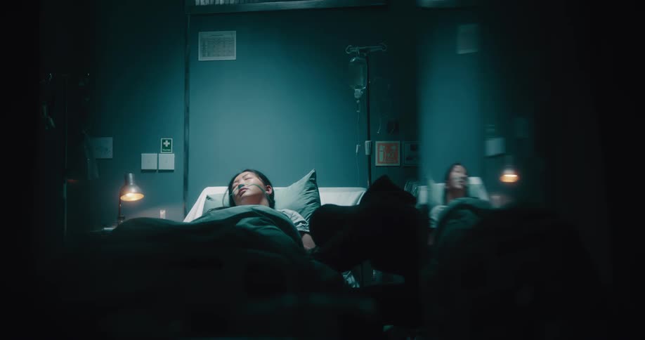 Depressed man next to his wife who is sleeping on a hospital stretcher