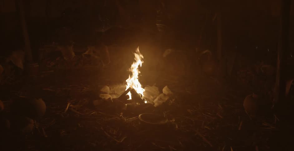 A small campfire burning at night surrounded by rocks