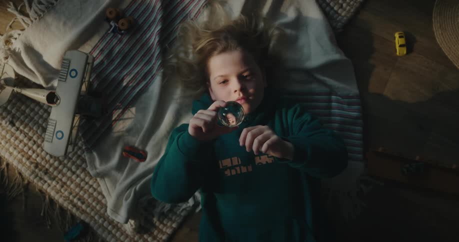 Girl lying on the floor holding a small crystal ball and gazing at it
