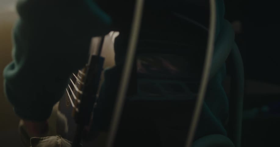 A young girl strums on her acoustic guitar while sitting indoors