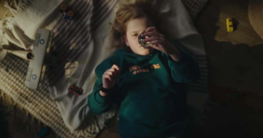 Child lying on bed examines a glass globe