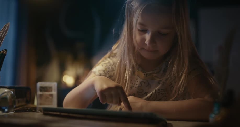 A blonde girl using a tablet in the evening