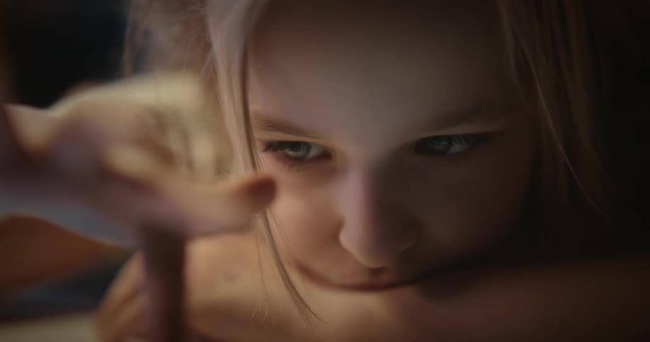 A sad young girl tapping on a tablet computer