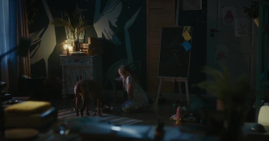 Blonde girl pets brown dog in her dim lit room