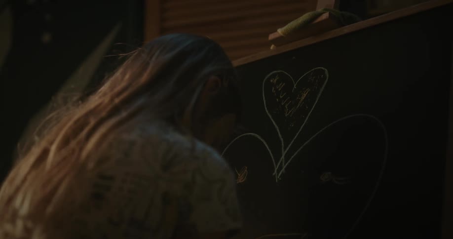 Blonde girl draws heart shaped face on chalkboard