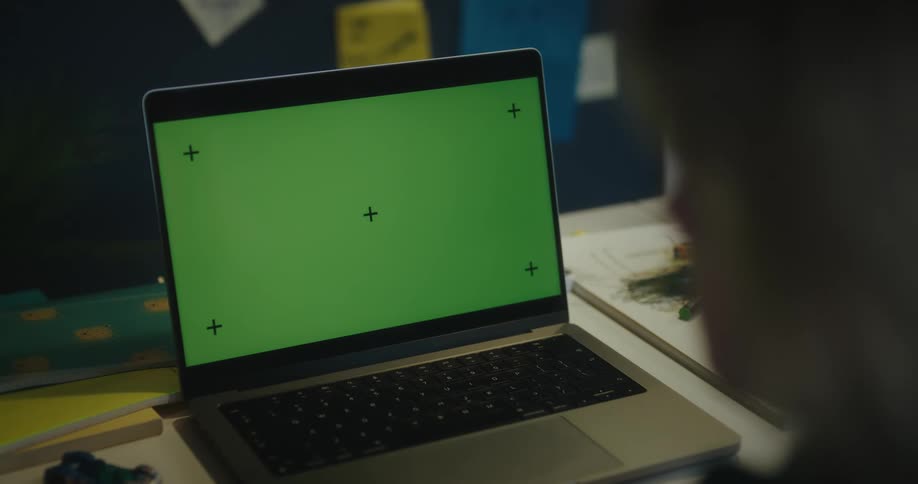 A laptop displaying a green screen