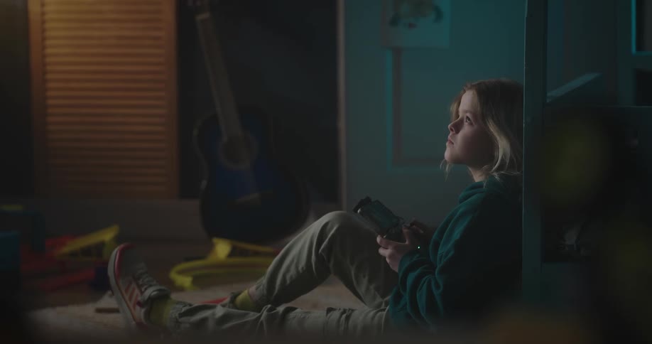 Child sitting controlling a drone with a remote control