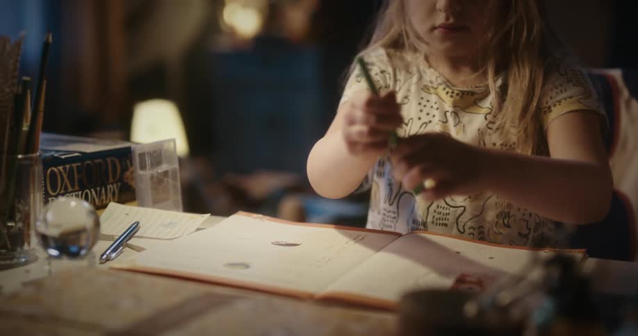 A little blonde girl drawing concentrated at a table
