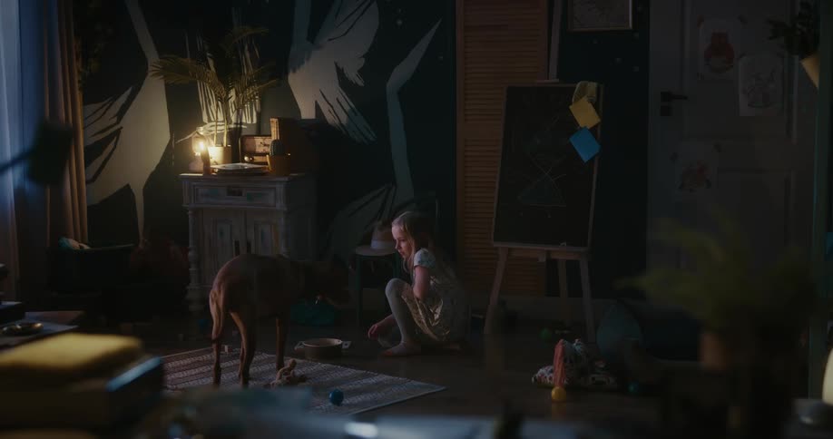 Blonde girl gives dog food in her dim lit room