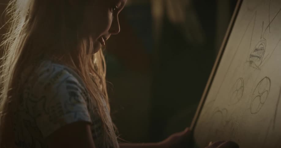 Blonde girl draws on a blackboard