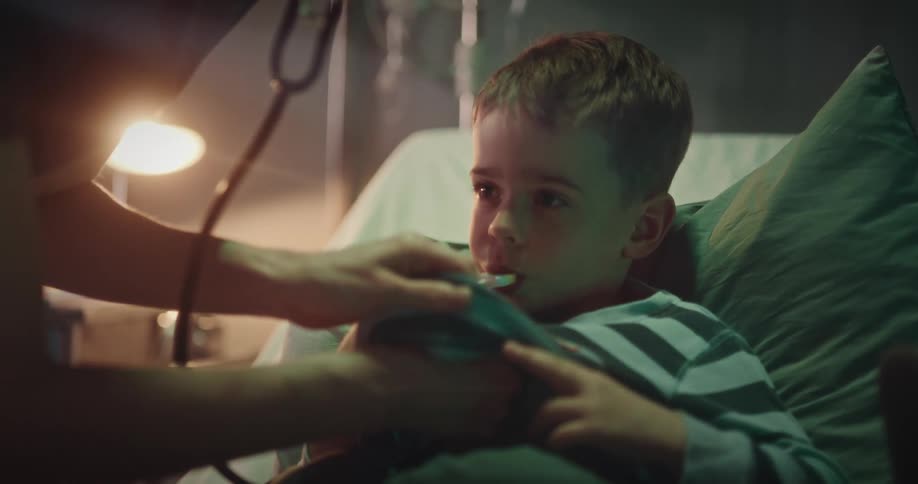 Nurse checks a boy resting in a hospital bed