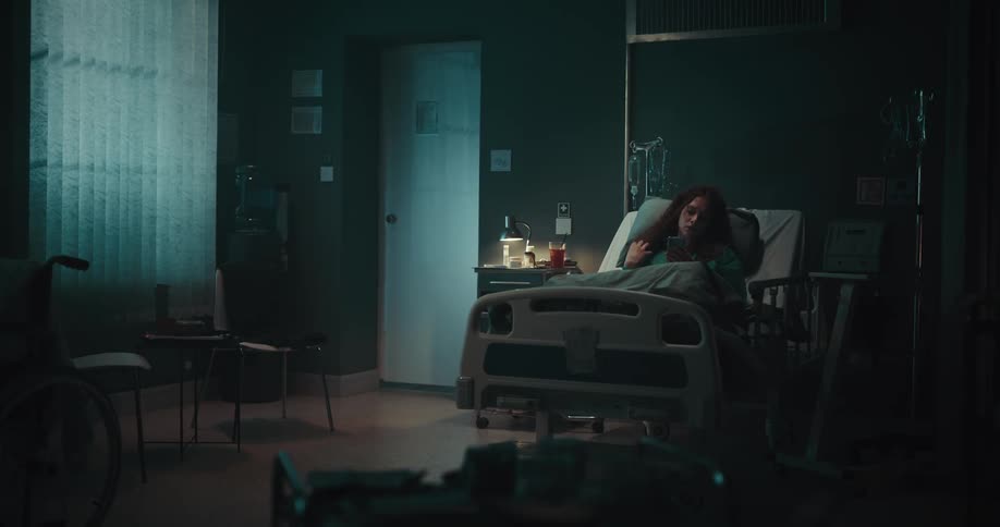 Female lays in hospital bed in dim room
