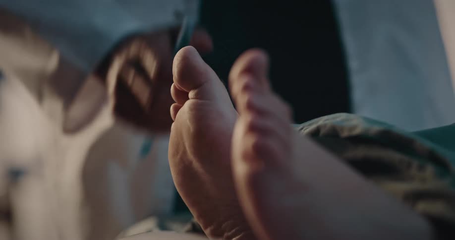 Doctor exams patients feet and talks to them in hospital bed