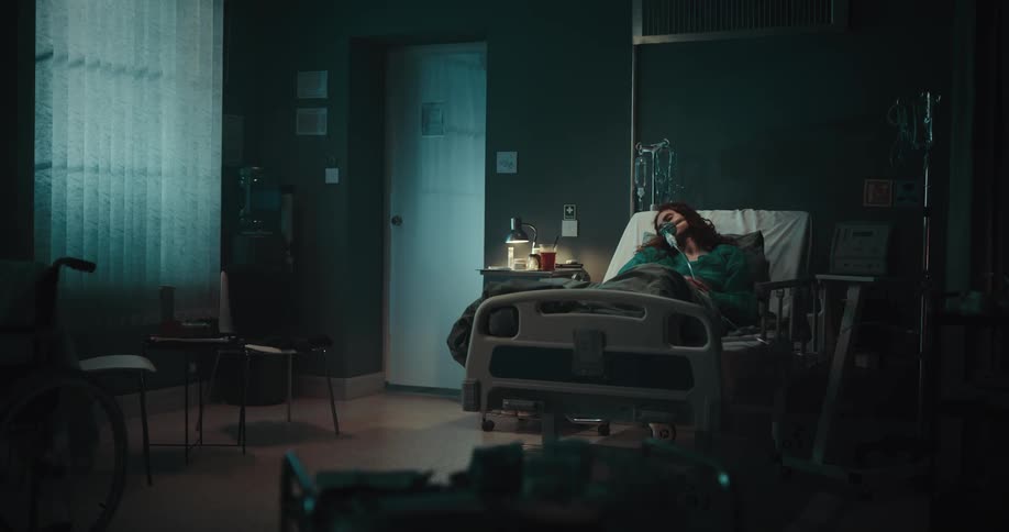 Female patient lying in a hospital bed with an oxygen mask