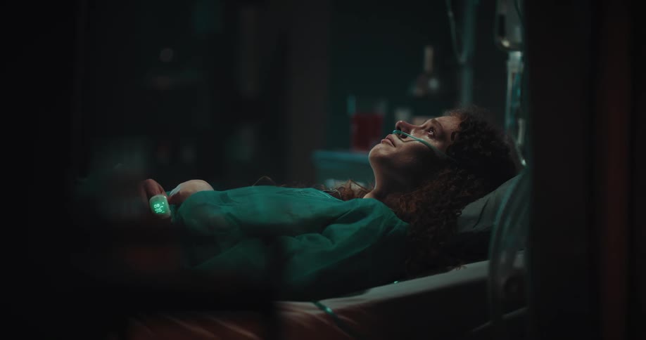 A woman is lying in a hospital bed with a tube in her nose