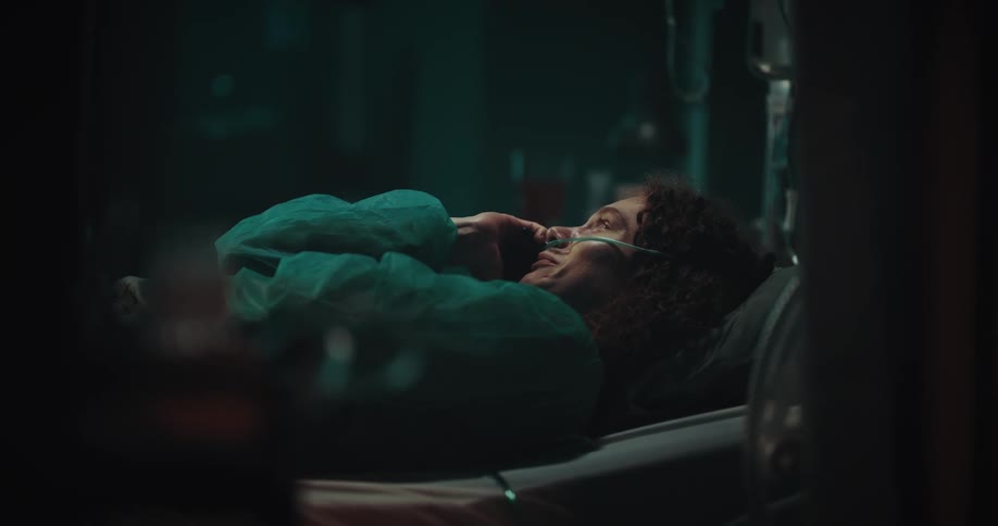 Woman lying in a hospital bed with a nasal catheter crying and talking on the phone