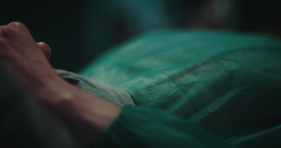 A woman is lying in a hospital bed and has a puff of breath in her nose