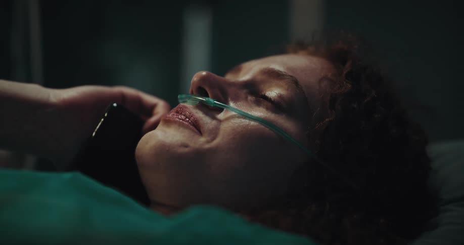 Female hospital patient lying on bed cries during phone call