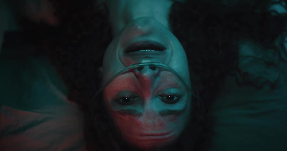 A woman lying down has a tube in her nose and is crying