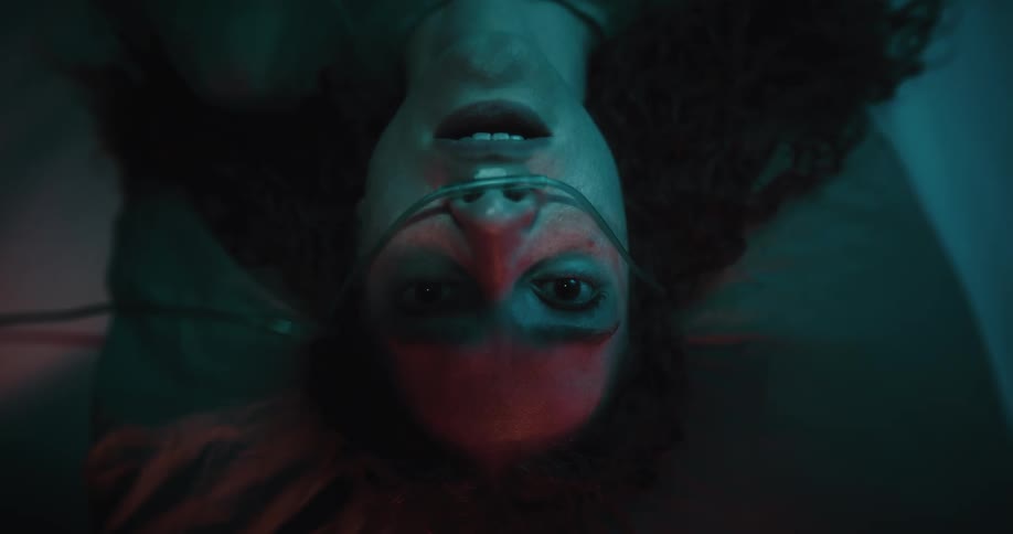 A woman in a dark room wearing endotracheal tube wakes up in fear as she breath heavily