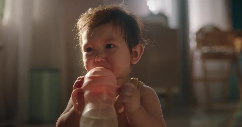 Portrait of a baby girl drinking water from a bottle and spitting it out