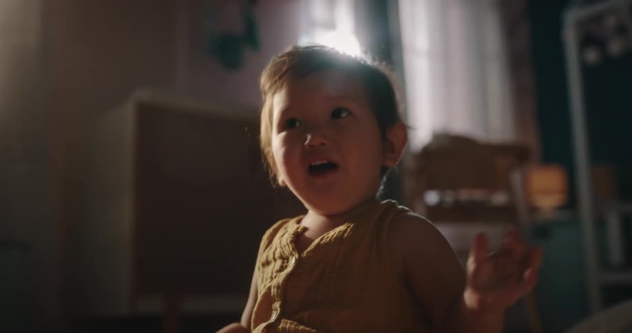 A baby sitting on the floor biting a bowl