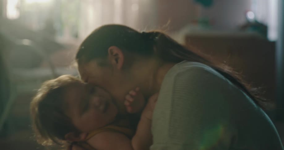 A woman is playing with her baby who is on her lap and they are both smiling
