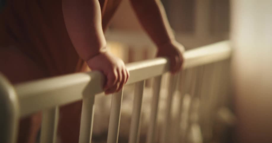 Toddler stands in a crib