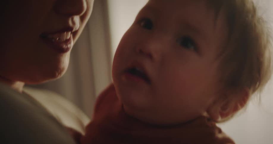 A mother with her baby on her lap and both are smiling affectionately