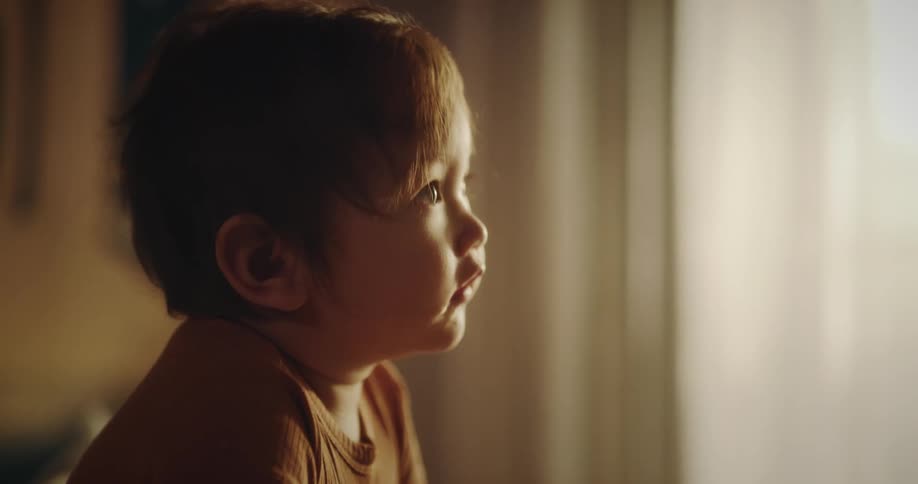 A child stands in his crib while looking around