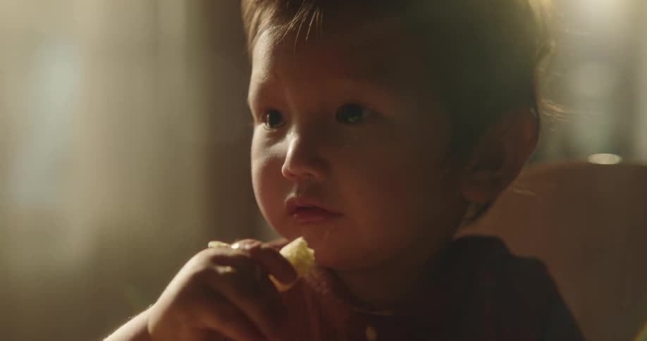 A toddler eating in a faintly dark room