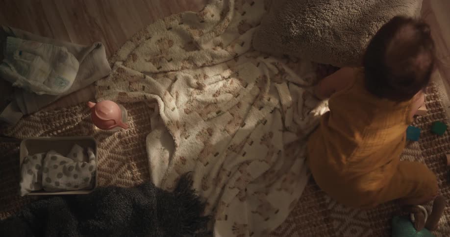 Baby crawling amidst blankets on the floor