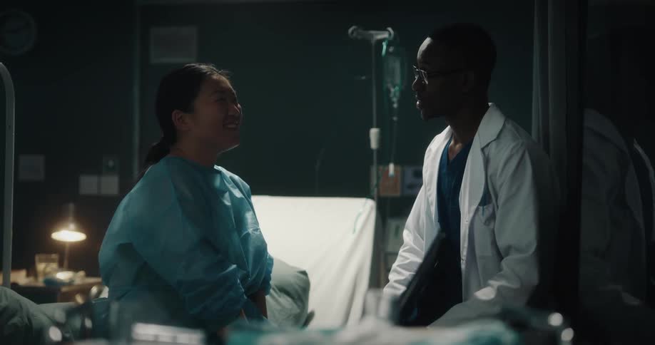 A doctor and a nurse talking in front of a hospital bed