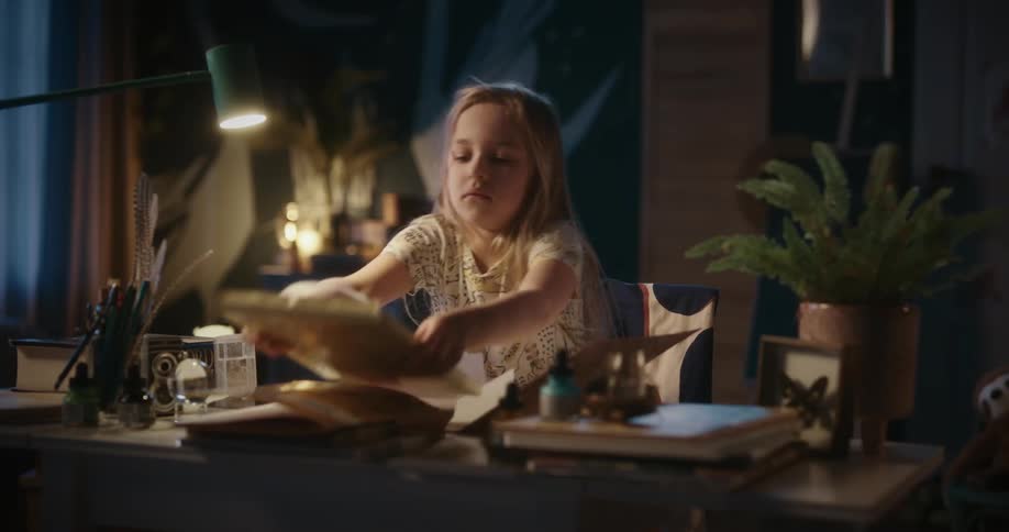 A little blonde girl is closing an envelope with paper