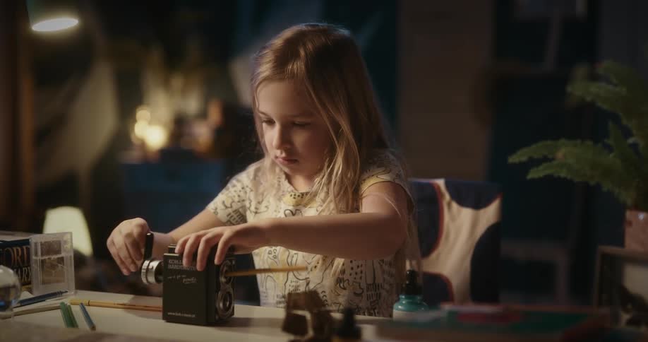 Female child sharpens a pencil with a black tool on the table