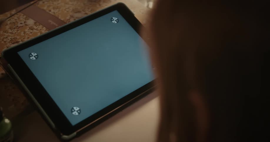 A persons head is moving near a tablet with a replacement screen on a table